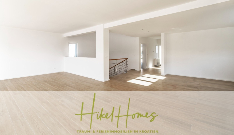 5 Sterne Villa Bruna – Meerblick auf 260m² WFL in 1. Reihe / 4 SZ / Neubau / Sofort bezugsfertig - Ein geräumiger, leerer Raum mit hellem Holzfußboden, weißen Wänden, großen Fenstern, die Sonnenlicht hereinlassen, und einem Metallgeländer neben einer Treppe. Der Text "Hikel Homes Traum- & Ferienimmobilien in Kroatien" ist am unteren Rand eingeblendet. (46354)