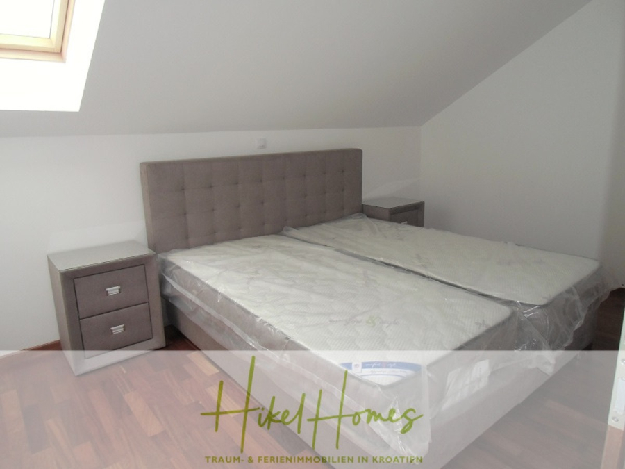 Appartement über 2 Stockwerke / 3 Schlafzimmer / 70m zum Meer / Pool / große Terrasse - Ein modernes Schlafzimmer mit einem Doppelbett, einem grau gepolsterten Kopfteil, zwei weißen Nachttischen und einem Holzfußboden. Die Bettmatratzen sind mit Kunststoff bezogen. Das Zimmer hat eine schräge Decke und ein Oberlichtfenster. (46641)