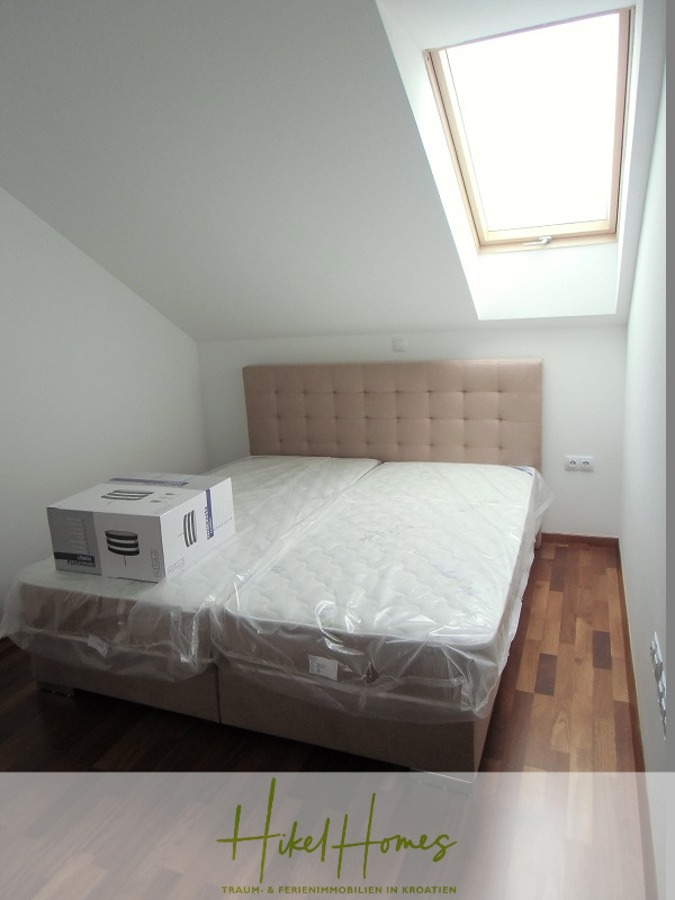 Appartement über 2 Stockwerke / 3 Schlafzimmer / 70m zum Meer / Pool / große Terrasse - Ein kleines Schlafzimmer mit Holzfußboden, einem Doppelbett mit beigefarbenem Polsterkopfteil, Matratzen, die noch in Plastik verpackt sind, einem Pappkarton auf dem Bett und einem Dachfenster über dem Bett, das Tageslicht hereinlässt. (46640)
