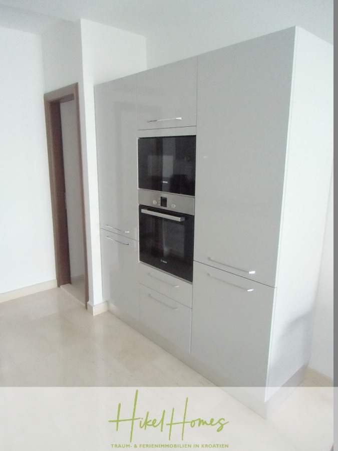 Appartement über 2 Stockwerke / 3 Schlafzimmer / 70m zum Meer / Pool / große Terrasse - Moderne weiße Einbauschränke mit einem Backofen und einer Mikrowelle aus Edelstahl vor einer hellen Wand und einem hellen Boden. Links neben den Schränken befindet sich eine Tür. (46636)