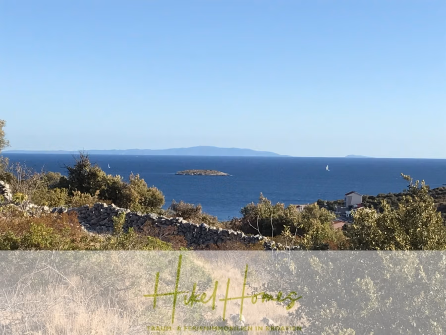 805m² Bauland in Panoramahanglage mit traumhaften Rundumblick aufs Meer und die vorgelagerten Inseln - Ein malerischer Blick auf das Meer mit kleinen Segelbooten in der Ferne unter einem klaren blauen Himmel. Kleine Felsinseln liegen verstreut im Wasser, im Vordergrund sind trockene Vegetation und Steinmauern zu sehen. Am Horizont sind entfernte Landschaftsformen zu erkennen. (42883)