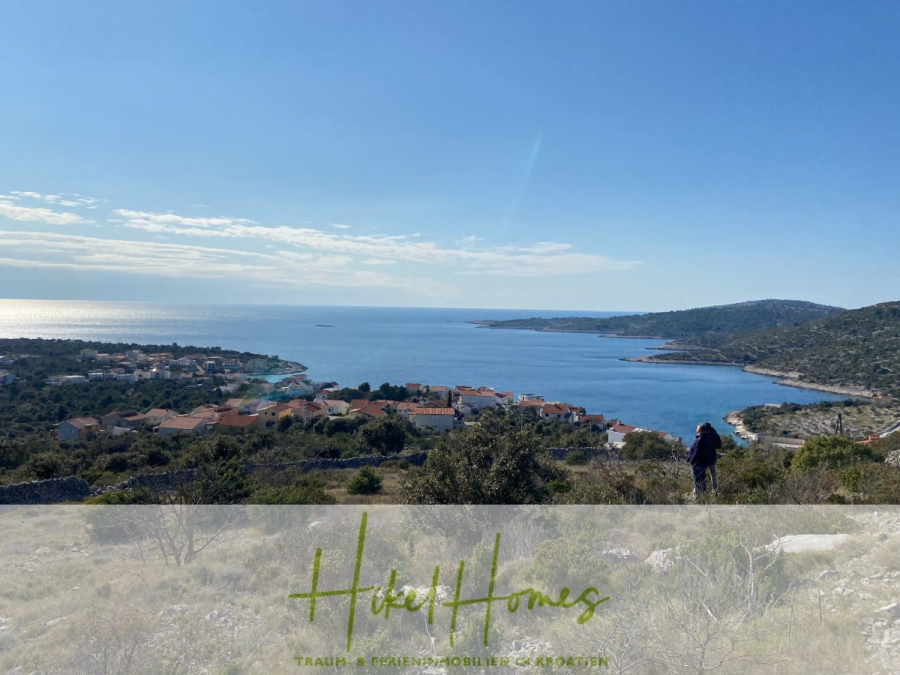805m² Bauland in Panoramahanglage mit traumhaften Rundumblick aufs Meer und die vorgelagerten Inseln - Eine Person steht auf einem Hügel mit Blick auf ein Küstendorf, mit blauem Meer, grünen Hügeln und einem klaren Himmel im Hintergrund. Das Bild enthält den Text "Hikel Homes TRAUM + FERIENIMMOBILIEN & WOHNEN" am unteren Rand. (44613)