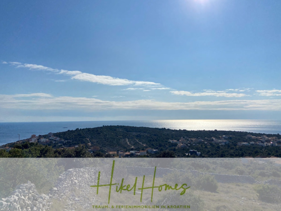 805m² Bauland in Panoramahanglage mit traumhaften Rundumblick aufs Meer und die vorgelagerten Inseln - Eine malerische Küstenlandschaft mit einem grünen Hügel, verstreuten Häusern und dem Meer, das unter einem strahlend blauen Himmel schimmert. Der Text "Hikel Homes Traum- & Ferienimmobilien in Kroatien" erscheint am unteren Rand. (44620)