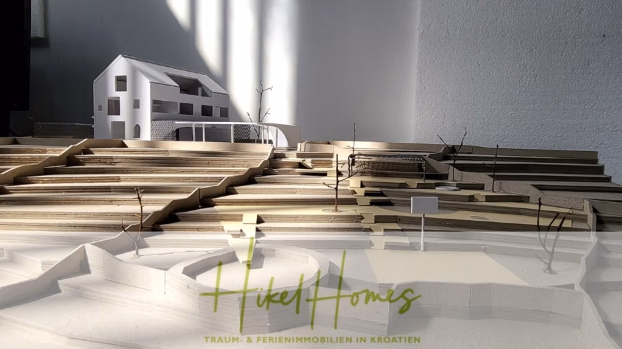Prämiertes Architekturprojekt – Meerblick Luxus auf 490m² auf 1800m² Grund mit 2 Pools, Bar, Lounge - Maßstabgetreues Modell einer Hügellandschaft mit einem modernen weißen Gebäude und Wegen. Die Basis besteht aus geschichteten Materialien, die teilweise an Holz erinnern. Licht wirft Schatten auf das Modell. Unten ist der Text „Hikel Homes“ sichtbar. (41178)