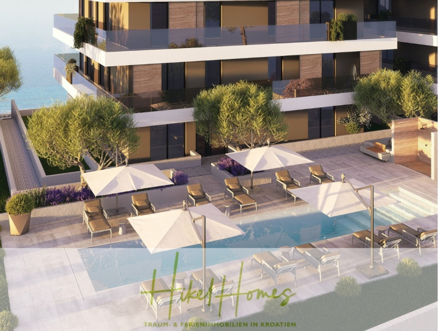 1. Reihe hochwertige Neubau-Meerblick Wohnung mit 2 SZ, Terrasse und Gemeinschaftspool (S2A) - Modernes Apartmentgebäude mit Balkonen und Blick auf einen rechteckigen Swimmingpool, umgeben von Liegestühlen, Sonnenschirmen und gepflegten Grünanlagen. Der Text "Hikel Homes" und "Traum- & Ferienimmobilien in Kroatien" erscheint am unteren Rand. (46116)