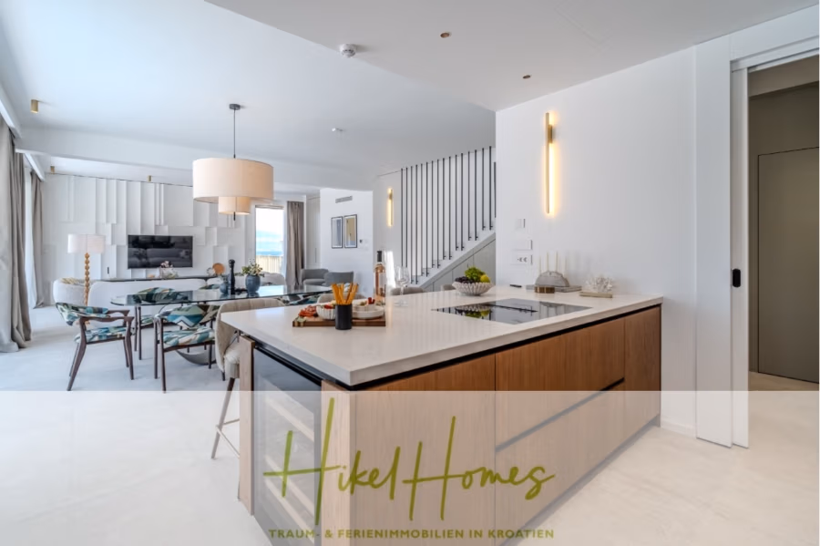 Schlüsselfertige Meerblick Villa SEA in Sutivan (Insel Brac) – 3 SZ + Bad, Pool, Sommerküche, … - Moderner, offener Wohnbereich mit Kücheninsel, Esstisch und gemütlichen Sitzgelegenheiten. Große Fenster sorgen für viel Tageslicht. Stilvolles Dekor in Weiß und Holz. Eine Treppe führt nach oben, eine minimalistische Wandleuchte schmückt die Wand. (43000)