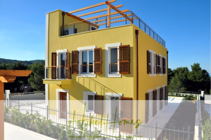 Villa im Mittelmeerstil mit 3 SZ, Pool, Dachterrasse mit Meerblick (2) - Leuchtend gelbes, dreistöckiges Haus mit Holzfensterläden und Dachterrasse. Umgeben von Grün und eingezäunt mit einem weißen Lattenzaun. Blauer Himmel und Bäume im Hintergrund, darunter der Schriftzug „Happy Homes“. (41868)