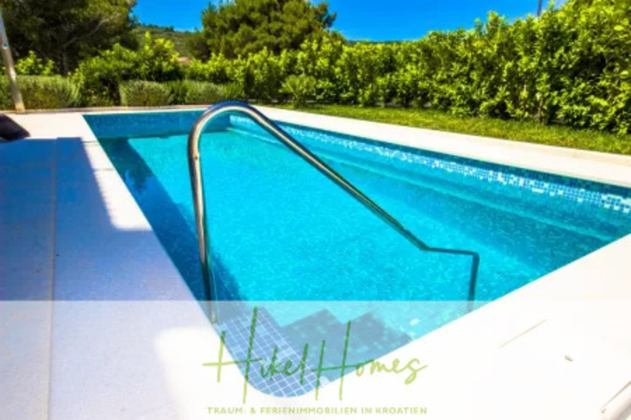 Villa im Mittelmeerstil mit 3 SZ, Pool, Dachterrasse mit Meerblick (2) - Ein klarer blauer Swimmingpool mit Stufen und einem Metallgeländer, umgeben von Grün und Büschen an einem sonnigen Tag. "Hikel Homes" und deutscher Text sind am unteren Rand des Bildes eingeblendet. (44796)