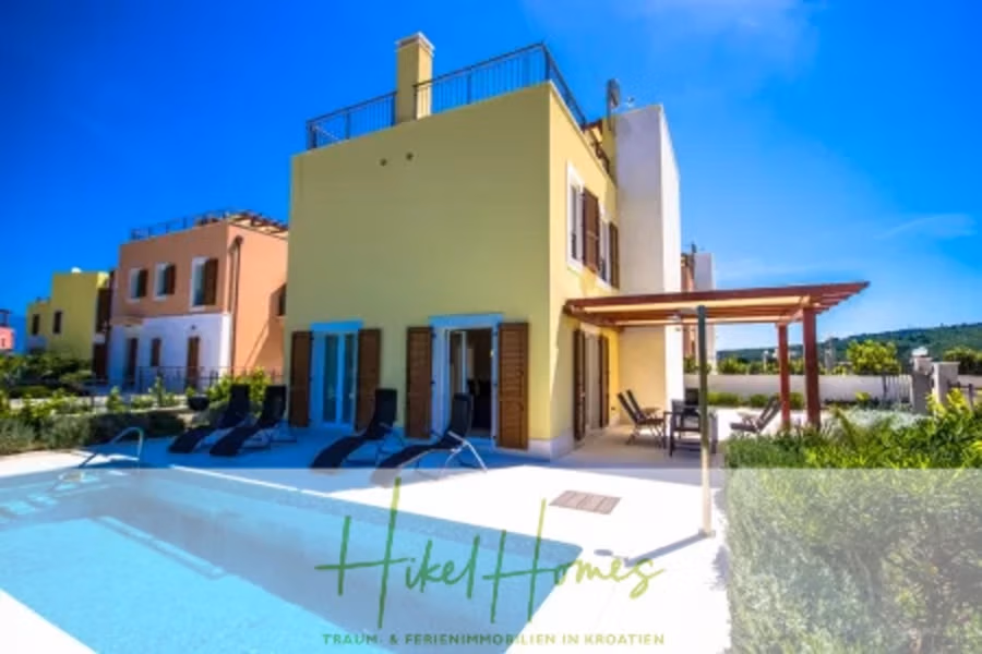 Villa im Mittelmeerstil mit 3 SZ, Pool, Dachterrasse mit Meerblick (2) - Moderne Villa mit Swimmingpool, umgeben von Sonnenliegen und einer Terrasse mit Pergola. Das Haus hat beige-gelbe Wände und große Fenster. Blauer Himmel und Grün im Hintergrund. Der Text „Hikel Homes“ ist über das Bild gelegt. (41869)