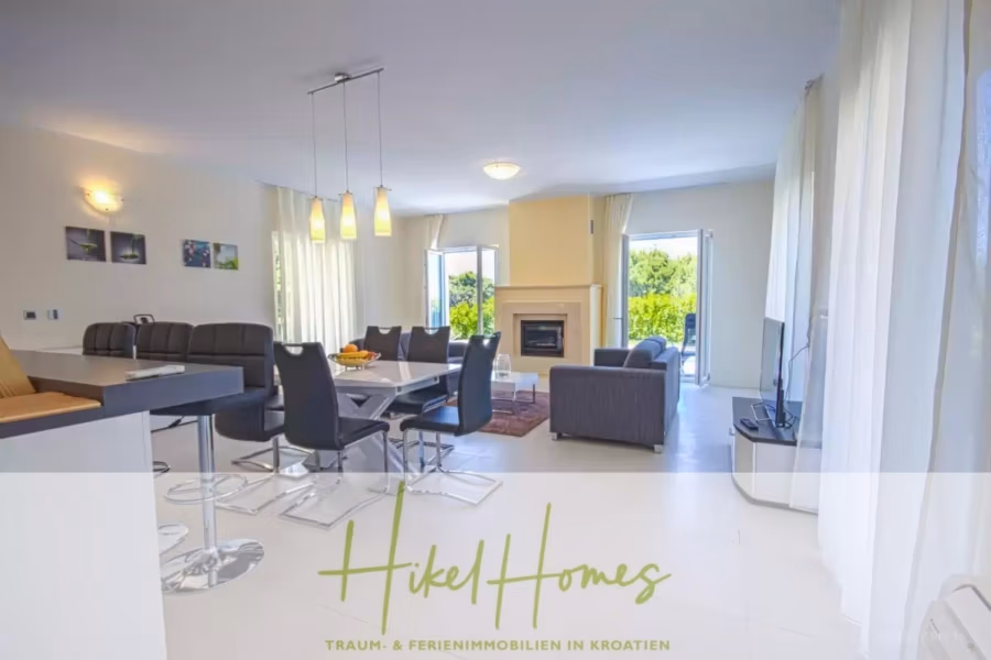 Villa im Mittelmeerstil mit 3 SZ, Pool, Dachterrasse mit Meerblick (2) - Helles, modernes, offenes Wohnzimmer mit offener Küche und Essbereich. Es verfügt über eine gemütliche Sitzecke mit Kamin, große Fenster, weiße Wände und elegante Möbel. Unten befindet sich das Logo „Hikel Homes – Traum & Ferienimmobilien in Kroatien“. (41882)