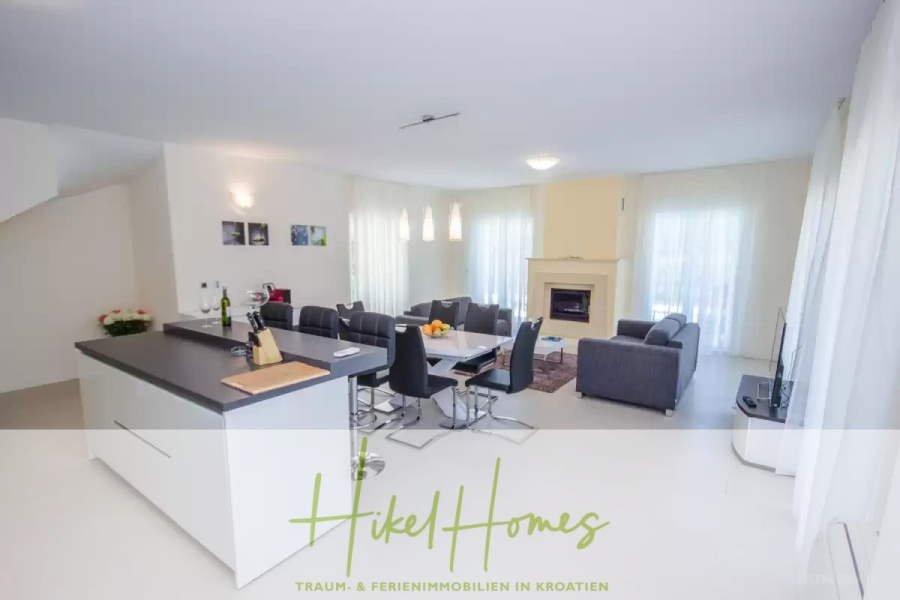Villa im Mittelmeerstil mit 3 SZ, Pool, Dachterrasse mit Meerblick (2) - Modernes, offenes Wohnzimmer und Küche mit einer großen Insel, Esstisch, grauen Sofas, Kamin und bodenlangen Vorhängen. Der Raum ist hell mit natürlichem Licht aus großen Fenstern. Die Textüberlagerung lautet "Hikel Homes". (44800)