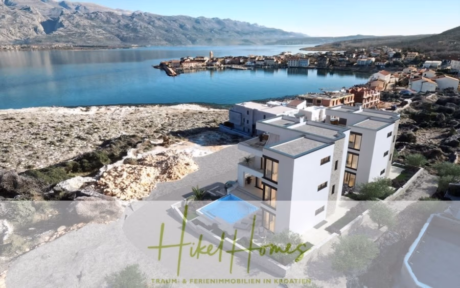 Luxus-Meerblick und Gebirgsblick-Villa in 2. Reihe zum Meer mit 4 SZ, Pool, Sauna, Fitness & Jacuzzi - Luftaufnahme moderner weißer Gebäude in der Nähe eines kroatischen Küstendorfes mit einem rechteckigen Pool im Vordergrund. Im Hintergrund ist eine ruhige Bucht zu sehen, umgeben von sanften Hügeln. Der Text unten lautet: „Hike Homes: Traum- & Ferienimmobilien in Kroatien.“. (42058)