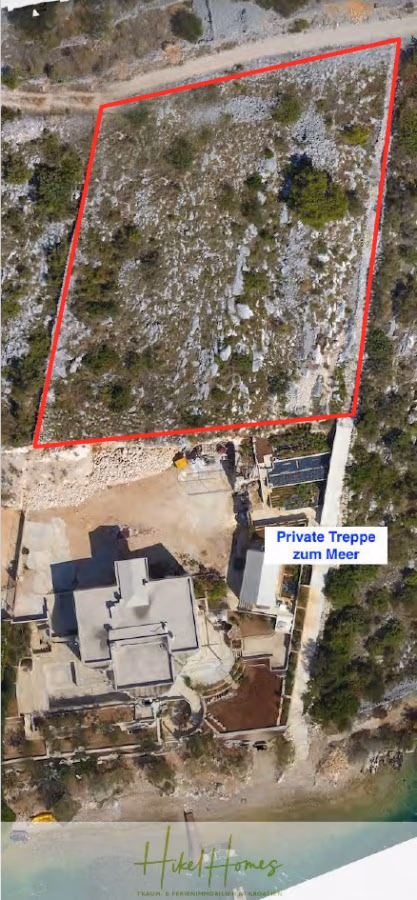 Einmaliges 2. Reihe mit Meerzugang 1834m² Bauland mit Baugenehmigung für 2 Villen - Luftaufnahme eines Küstengrundstücks mit einem modernen Haus, einem markierten, rot umrandeten Grundstück und einem Weg mit der Aufschrift „Private Treppe zum Meer“, der zum Meer führt. Die Umgebung ist spärlich bewachsen und felsig. (43222)