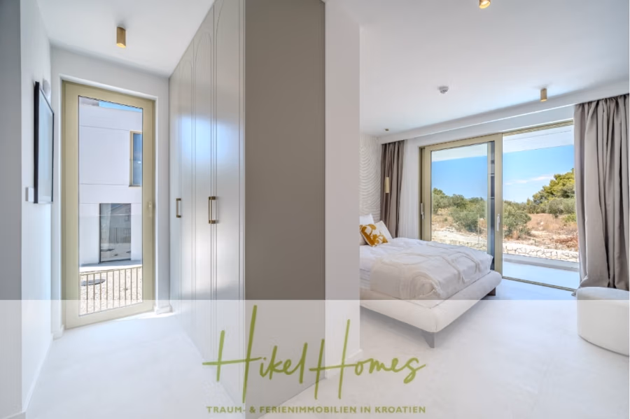 Hochwertige Meerblick Villa SUN in Sutivan (Insel Brac) – 3 SZ + Bad, Pool, Sommerküche, WC, … - Helles, modernes Schlafzimmer mit großem Bett, Glastüren und minimalistischer Einrichtung. Helle Wände, Kleiderschrank und Vorhänge. Durch die Fenster bietet sich ein malerischer Blick ins Grüne. Unten steht „Hikel Homes“. (42969)