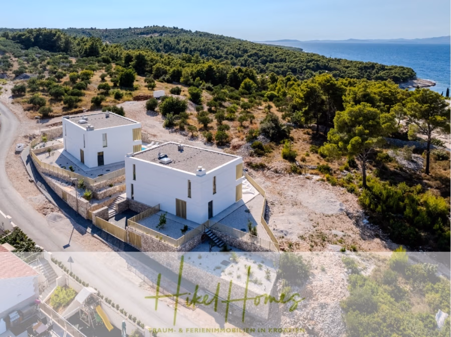 Hochwertige Meerblick Villa SUN in Sutivan (Insel Brac) – 3 SZ + Bad, Pool, Sommerküche, WC, … - Luftaufnahme zweier moderner weißer Häuser mit Flachdächern, umgeben von Grünflächen nahe der Küste. Eine kurvenreiche Straße verläuft daneben. Die Landschaft ist geprägt von Bäumen und felsigem Gelände unter einem klaren blauen Himmel. (42964)