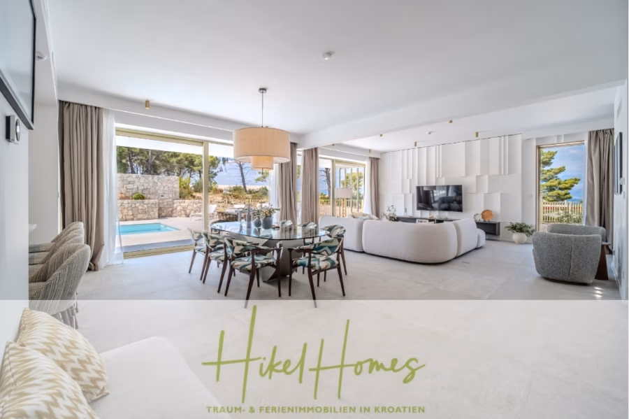 Hochwertige Meerblick Villa SUN in Sutivan (Insel Brac) – 3 SZ + Bad, Pool, Sommerküche, WC, … - Ein modernes, offenes Wohnzimmer mit Essbereich. Neutrale Farbtöne, ein Glas-Esstisch, gemusterte Stühle und ein großer Fernseher runden das Angebot ab. Schiebetüren führen zum Pool und zur Terrasse mit Panoramablick. Unten steht „Hikel Homes“. (42967)