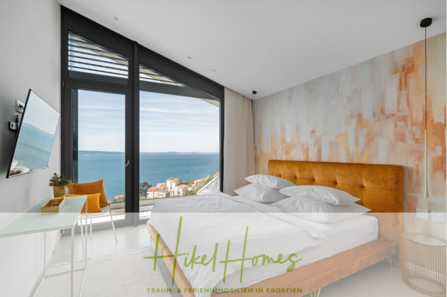Sofort einziehen! Meerblick Villa CECILIE Infinity Pool, 3 SZ, Sommerküche, Videoraum mit PS5, …. - Modernes Schlafzimmer mit großem Fenster und malerischem Meerblick, senffarbenem Bett, abstrakter Wandkunst und einem an der Wand montierten Fernseher. Das Zimmer ist hell, minimalistisch eingerichtet und in neutralen Tönen gehalten. (43915)