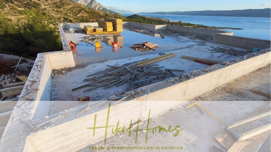 Schlüsselfertige – großzügige Meerblick Villa in ruhiger Lage, 4 SZ, 4 Bäder, Pool, Jacuzzi, … - Dach einer im Bau befindlichen Betonkonstruktion mit verstreuten Baumaterialien. Von der Konstruktion aus hat man einen malerischen Blick auf die Küste mit Bergen und einem Gewässer im Hintergrund. Unten ist der Text „Hikel Homes“ eingeblendet. (41020)