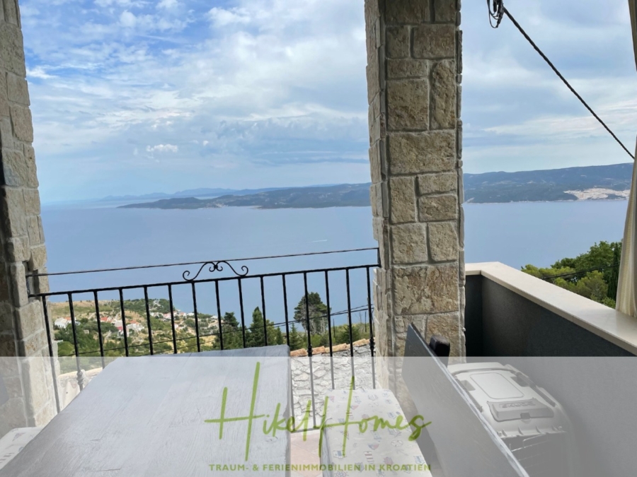 Meerblick aus perfekter Höhenlage mit 3 Schlafzimmern - Blick von einem Steinbalkon auf das Meer und die fernen Inseln. Im Vordergrund sind ein Esstisch und ein Eisengeländer zu sehen. Der Himmel ist teilweise bewölkt. Unten ist ein Logo mit der Aufschrift „Hiki Homes“ und zusätzlichem deutschen Text zu sehen. (41472)