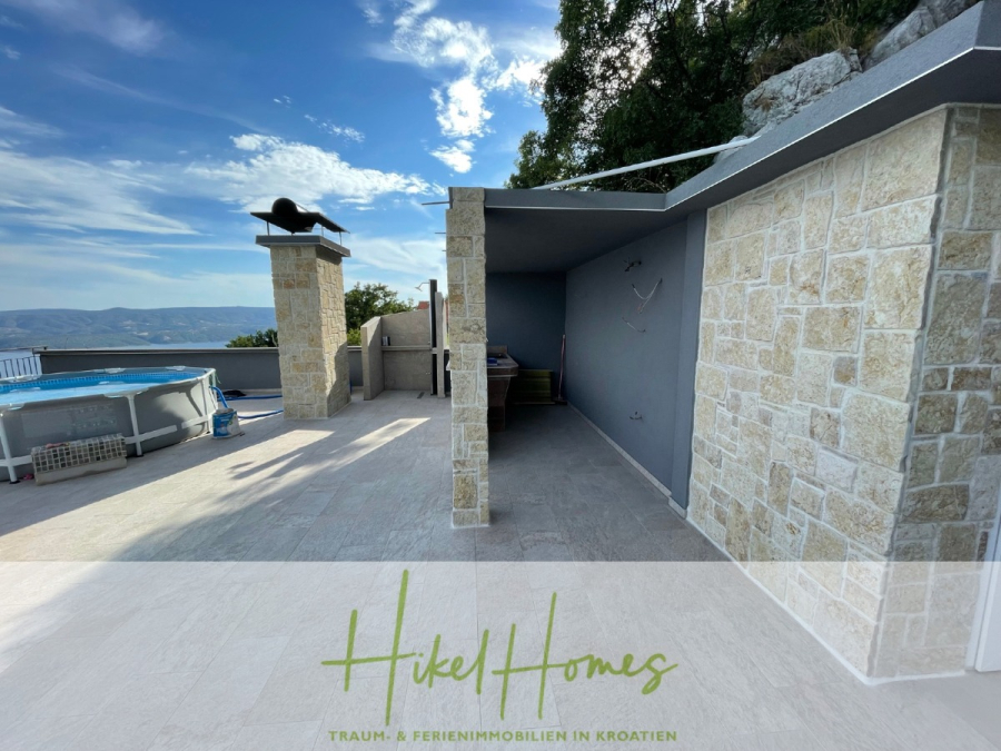 Meerblick aus perfekter Höhenlage mit 3 Schlafzimmern - Geräumige Außenterrasse mit Steinsäulen, einem überdachten Sitzbereich, einem kleinen oberirdischen Pool und Blick auf die Hügel unter blauem Himmel. Das Logo "Hikel Homes" und der deutsche Text sind am unteren Rand eingeblendet. (46073)