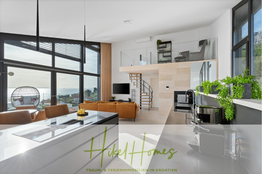 Direkt einziehen Meerblick Villa NATALIA mit Infinity Pool, 3 SZ, Sommerküche, … - Moderner, sonnendurchfluteter Wohnraum mit raumhohen Fenstern, Meerblick, Loftbereich mit Arbeitsbereich, hellbraunen Sofas, Kücheninsel, Zimmerpflanzen und einem Hängesessel am Fenster. Das Logo von „Hikel Homes“ überlagert das Bild. (43880)