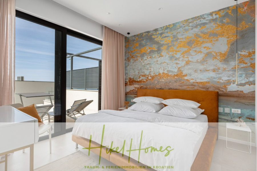Direkt einziehen Meerblick Villa NATALIA mit Infinity Pool, 3 SZ, Sommerküche, … - Ein modernes Schlafzimmer mit einem braunen Polsterbett, weißer Bettwäsche und einer strukturierten orange-blauen Akzentwand. Große Glastüren öffnen sich zu einem Balkon mit Sitzgelegenheiten im Freien und Blick auf einen sonnigen, blauen Himmel. (43876)