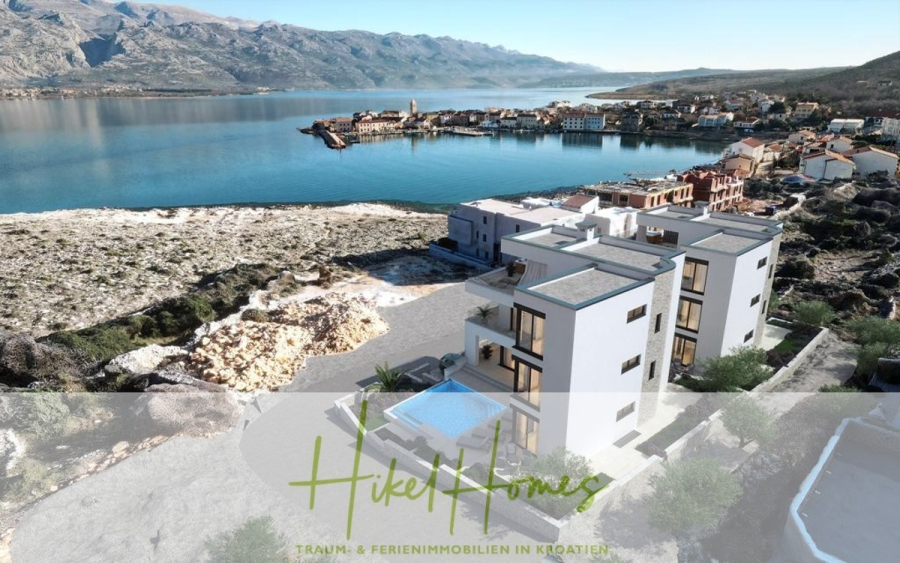 Nahe Zadar – Luxus-Villa in 2. Reihe zum Meer mit 4 SZ, Pool, Sauna, Fitness & Jacuzzi - Ein modernes weißes Apartmenthaus mit Pool überblickt eine Küstenstadt und ruhiges blaues Wasser, umgeben von felsigen Hügeln. Der überlagerte Text lautet "Hikel Homes - Traum- & Ferienimmobilien in Kroatien". (45960)