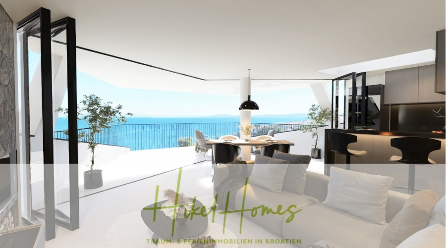Meerblick Penthouse mit außergewöhnlicher Architektur 104m² mit 2 SZ, Terrasse und Südausrichtung - Modernes, offenes Wohnzimmer und Küche mit großen Fenstern und Schiebetüren, die sich zu einer Terrasse mit Blick auf das Meer öffnen lassen; stilvolle Möbel, Hängeleuchten und eine malerische Aussicht auf die Küste. Der Text "Hikel Homes" ist überlagert. (46329)