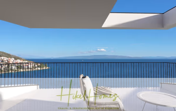 Eine moderne Terrasse mit Liegestuhl und rundem Tisch bietet unter einem klaren blauen Himmel Blick auf das tiefblaue Meer und die ferne Küste. Unten sind die Worte „Hike Homes“ und ein Slogan zu sehen. - Meerblick Penthouse mit außergewöhnlicher Architektur 104m² mit 2 SZ, Terrasse und Südausrichtung
