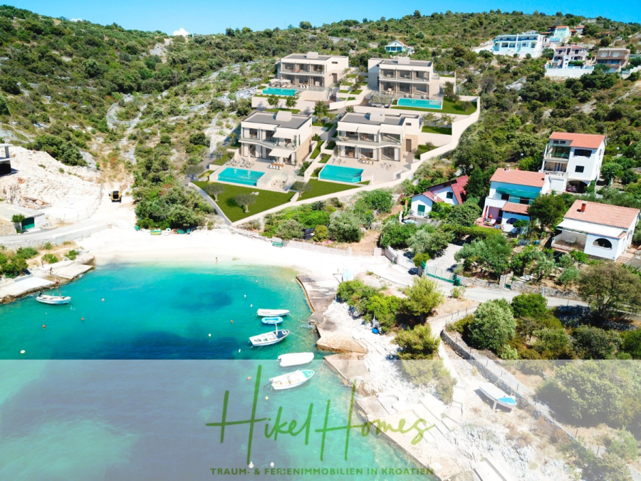 Villa Bettina – Luxus mit Blick auf Strand – Bucht – Meer / 3 Schlafzimmer / 3 Bäder - Luftaufnahme eines Küstendorfs in Kroatien mit modernen Villen, privaten Pools und grünen Hängen in der Nähe eines kleinen Sandstrands und klarem türkisfarbenem Wasser mit ankernden Booten. Die Worte "Hikel Homes Traum & Ferienimmobilien in Kroatien" erscheinen am unteren Rand. (46768)