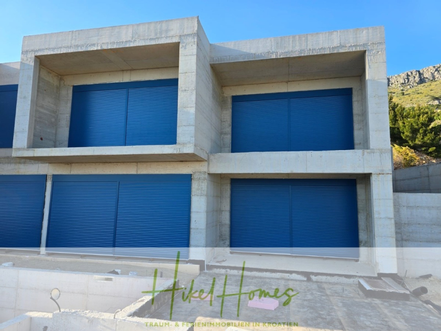 Schlüsselfertige – großzügige Meerblick Villa in ruhiger Lage, 4 SZ, 4 Bäder, Pool, … - Ein modernes Betongebäude mit großen blauen Fensterläden an den Fenstern und Türen. Das Gebäude ist unvollendet, und es gibt keine Bepflanzung oder Pflasterung vor dem Gebäude. Im Hintergrund sind Hügel und Grünflächen zu sehen. (45177)