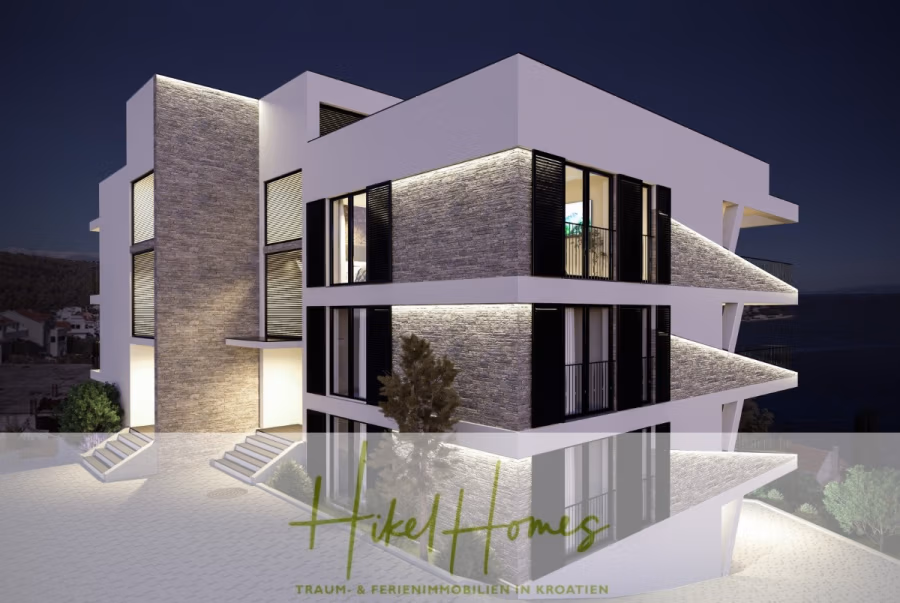 Luxus Meerblick 77m² Ensemble mit 2 Schlafzimmern, Terrasse und Südausrichtung (1. OG) - Modernes, mehrstöckiges Haus mit großen Fenstern und Steinakzenten, nachts beleuchtet. Im Hintergrund sind das Meer und ein Teil einer Küstenstadt zu sehen. Der Text unten lautet: „Hikel Homes – TRAUM- & FERIENIMMOBILIEN IN KROATIEN.“. (43844)