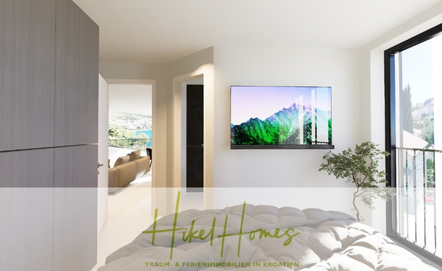 Luxus Meerblick 77m² Ensemble mit 2 Schlafzimmern, Terrasse und Südausrichtung (1. OG) - Modernes, helles Schlafzimmer mit einem an der Wand montierten Fernseher, der eine Berglandschaft zeigt, großen Fenstern mit Blick nach draußen und einem Blick auf ein Wohnzimmer mit einem Sofa. "Hikel Homes"-Logo und Textüberlagerung am unteren Rand. (46845)